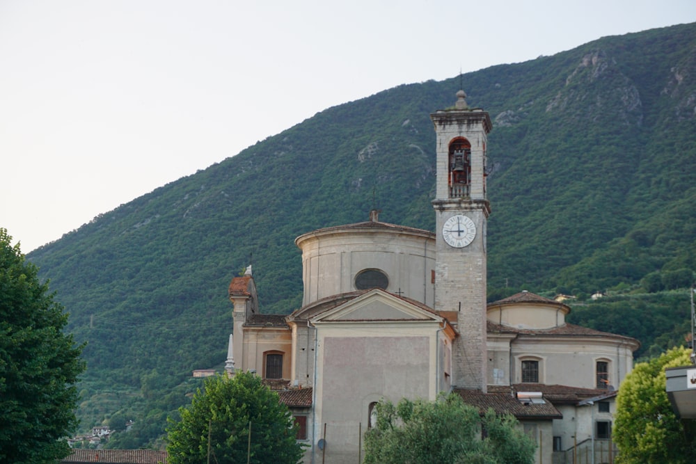 a church with a clock tower in front of a mountain