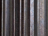 Close-up of a sleek metal panel with a deep black oxidation finish highlighting fine grain texture.