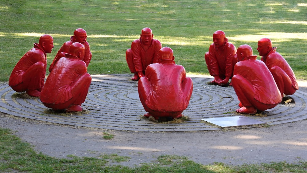 a group of red statues sitting on top of a circle