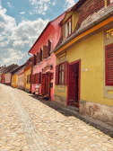 A cobblestone path winding through colorful baroque-style houses under a bright sky.