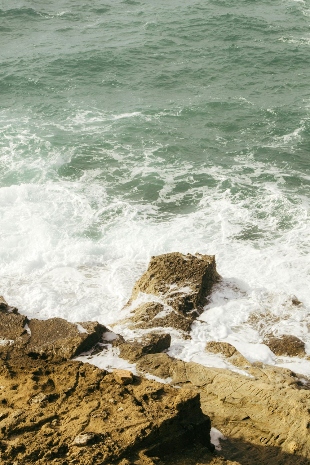 a person sitting on a rock next to the ocean