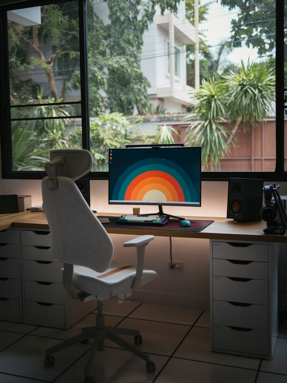 a desk with a computer on it in front of a window