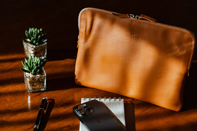 A sleek black leather folder resting on a wooden desk with soft natural light.
