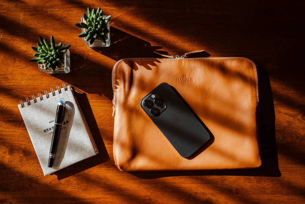 a cell phone sitting on top of a brown bag next to a pen
