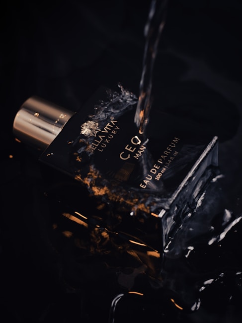 A dark-themed image featuring a bottle of perfume. The bottle has a luxurious design with the text 'CEO MAN' and 'EAU DE PARFUM'. Water droplets and splashes suggest a sense of freshness and vitality. The lighting highlights the sleek, reflective surface of the bottle, creating an elegant and sophisticated aesthetic.