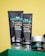 Close-up of three skincare products from the brand mCaffeine placed on a green surface against a yellow background. Two black tubes labeled 'naked & raw coffee face wash' and 'coffee face scrub' are prominently displayed along with a round container, also branded.