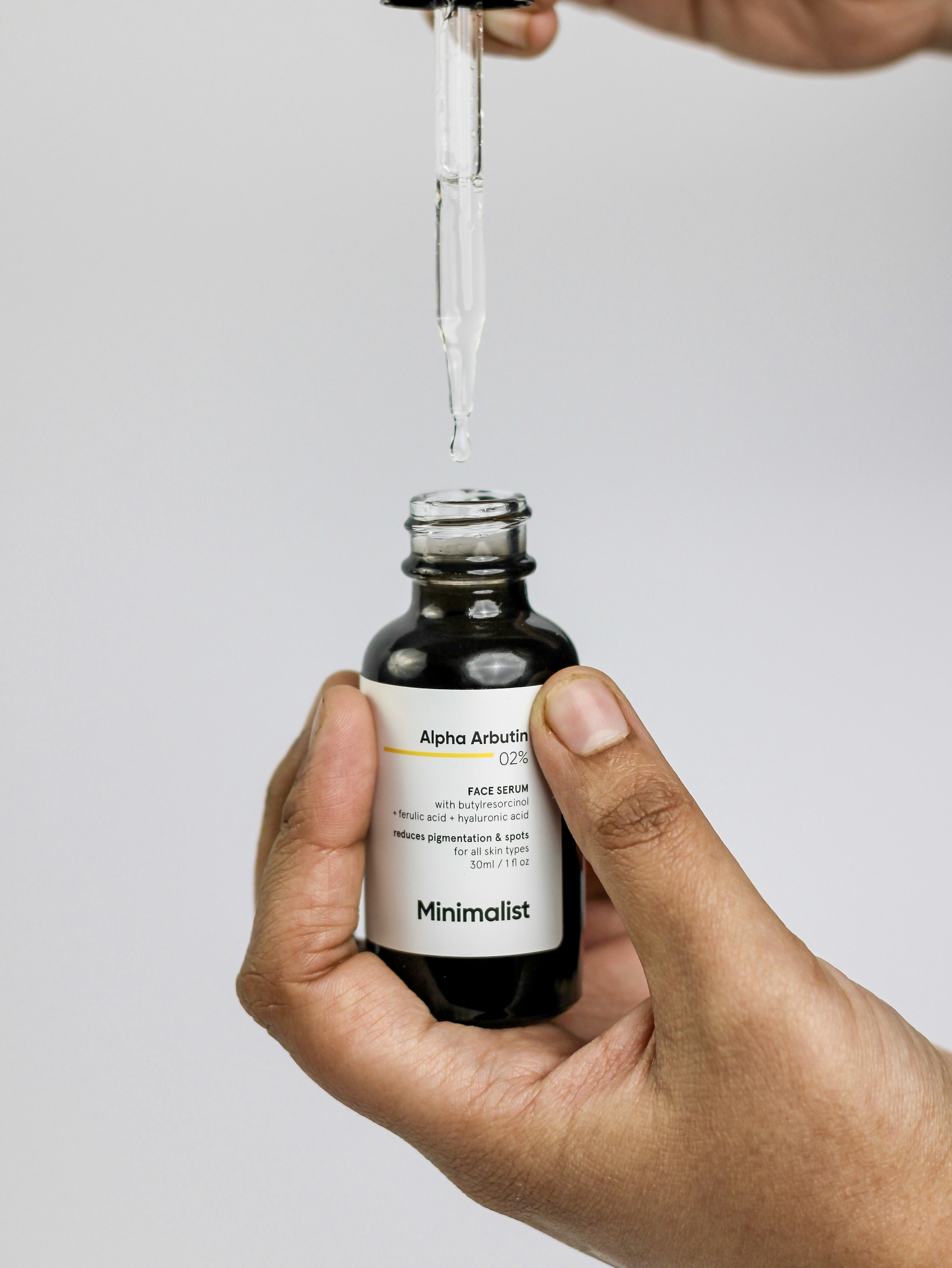 Close-up of a single amber dropper releasing a precise drop on clean surface, representing purposeful active formulation