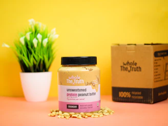 Flat lay of Vigoredge peanut butter jar alongside a protein bar and workout gloves on a dark surface.