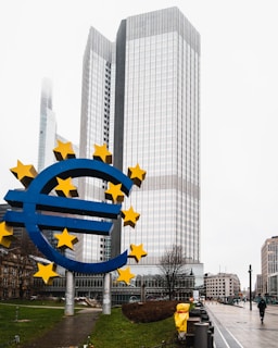 a large blue and yellow euro sign in front of a tall building