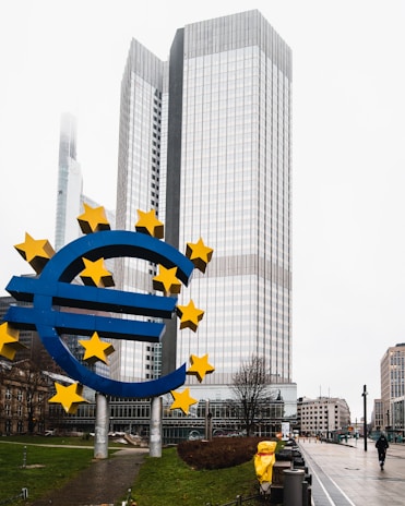 a large blue and yellow euro sign in front of a tall building