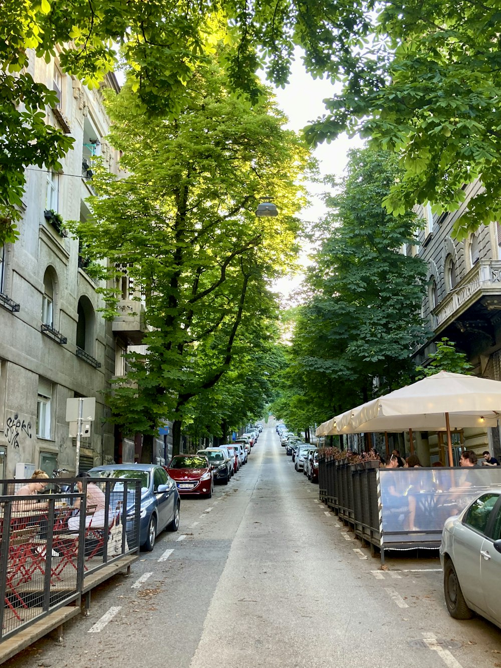 a street lined with parked cars next to tall buildings