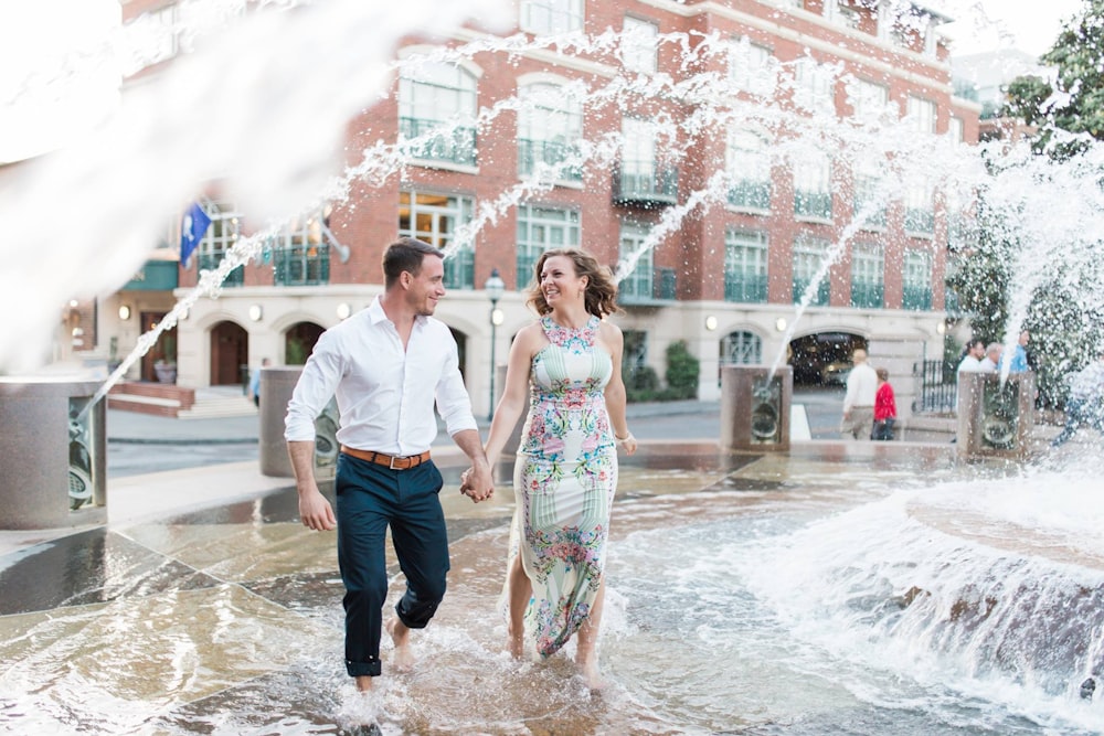 a man and a woman are walking through a fountain