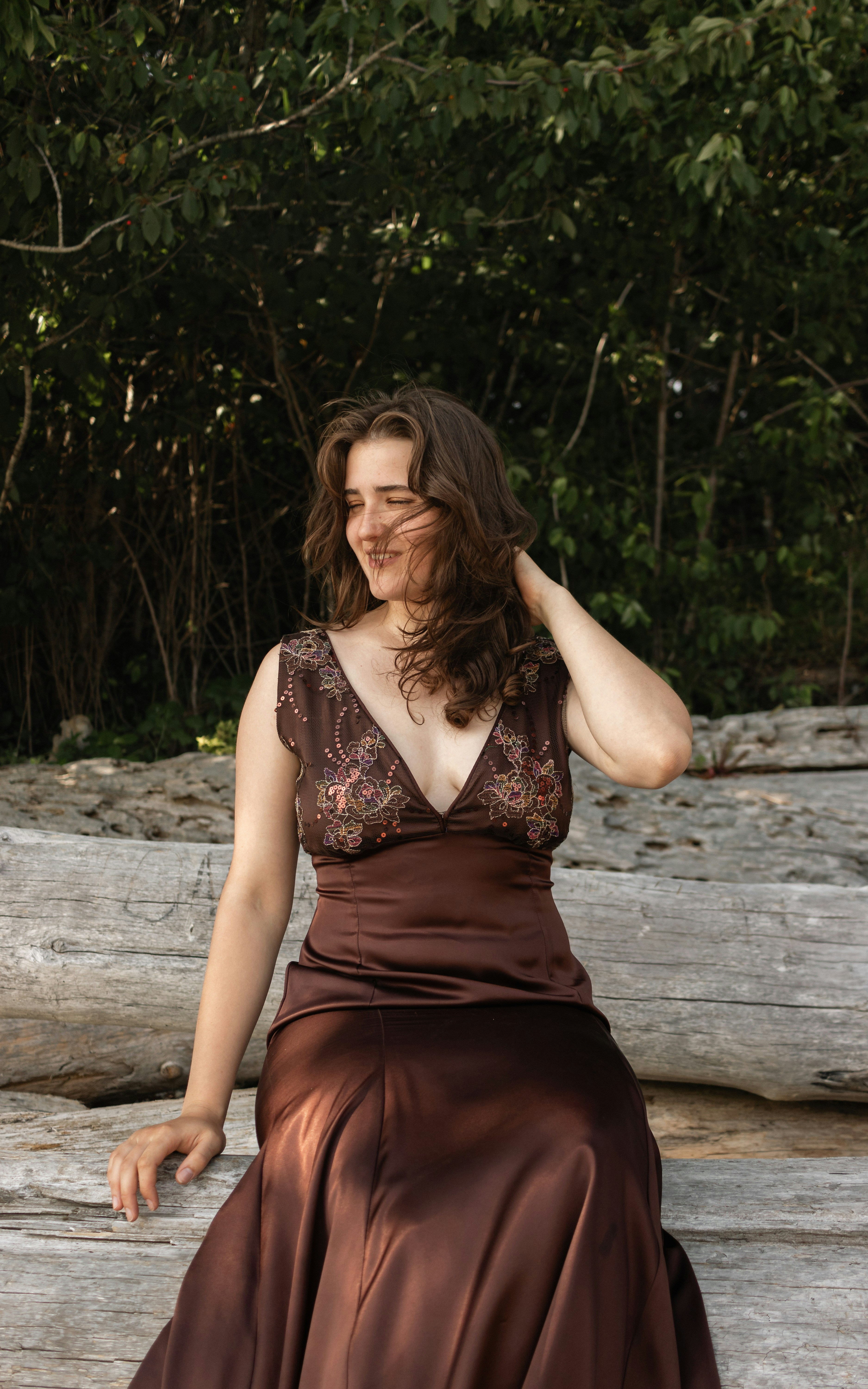a woman in a brown dress sitting on a log