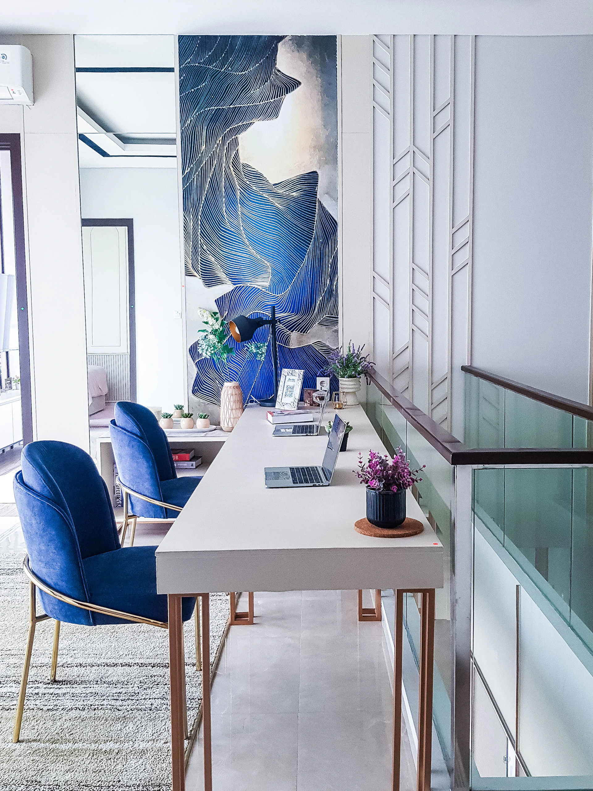a white table with blue chairs and a painting on the wall