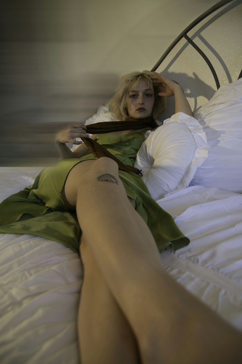 a woman in a green dress laying on a bed