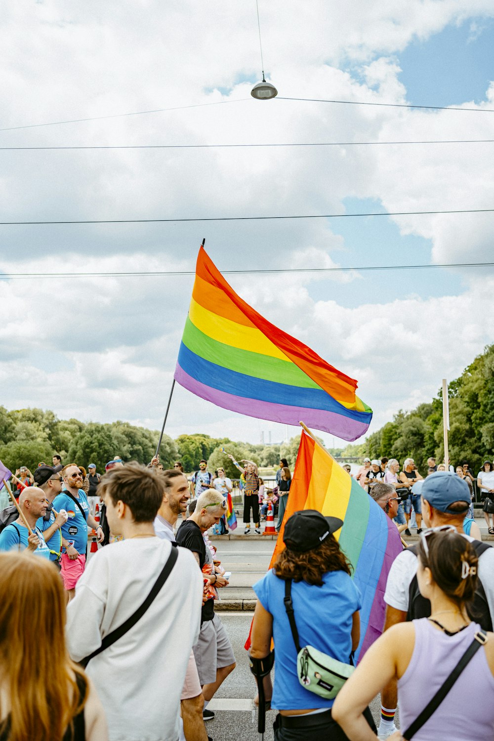 a group of people walking down a street holding a rainbow flag