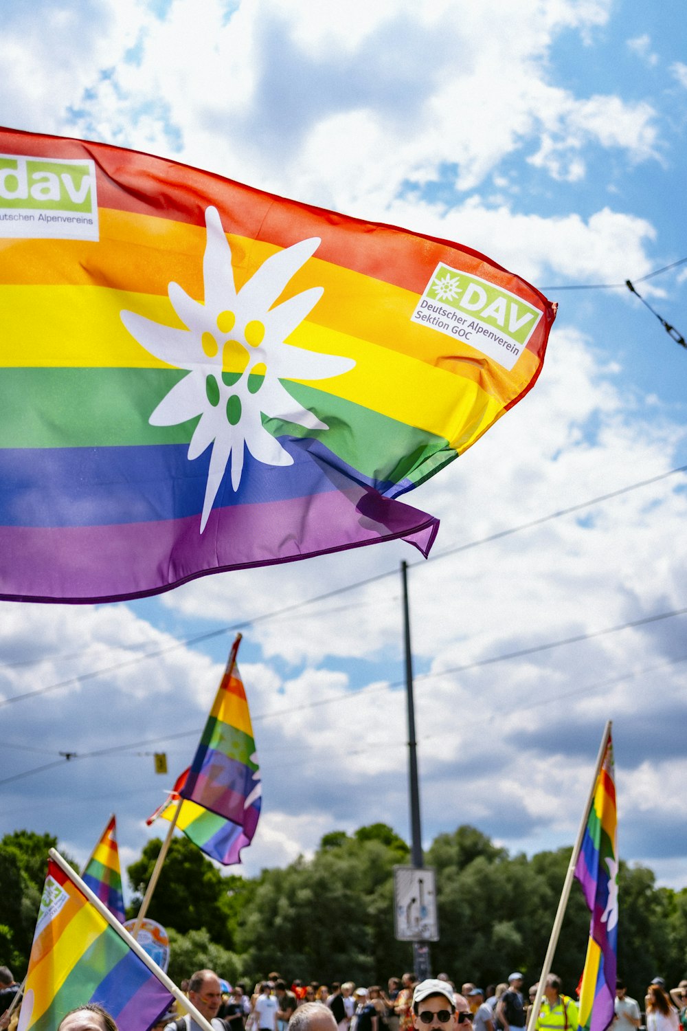 a crowd of people standing around a rainbow flag