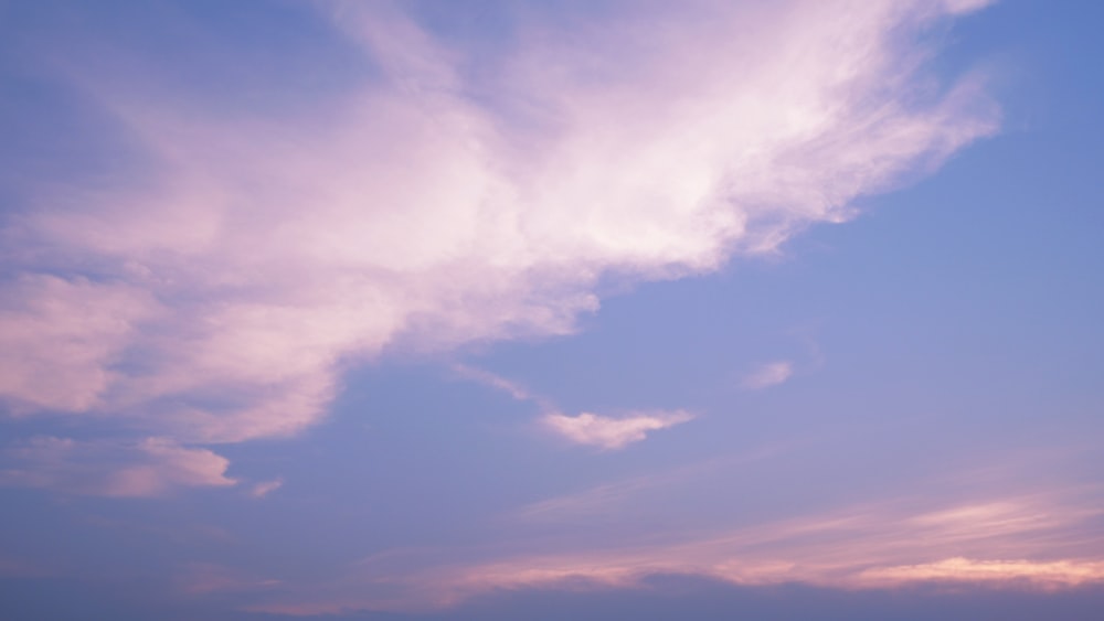 a plane flying in the sky with a pink and blue background