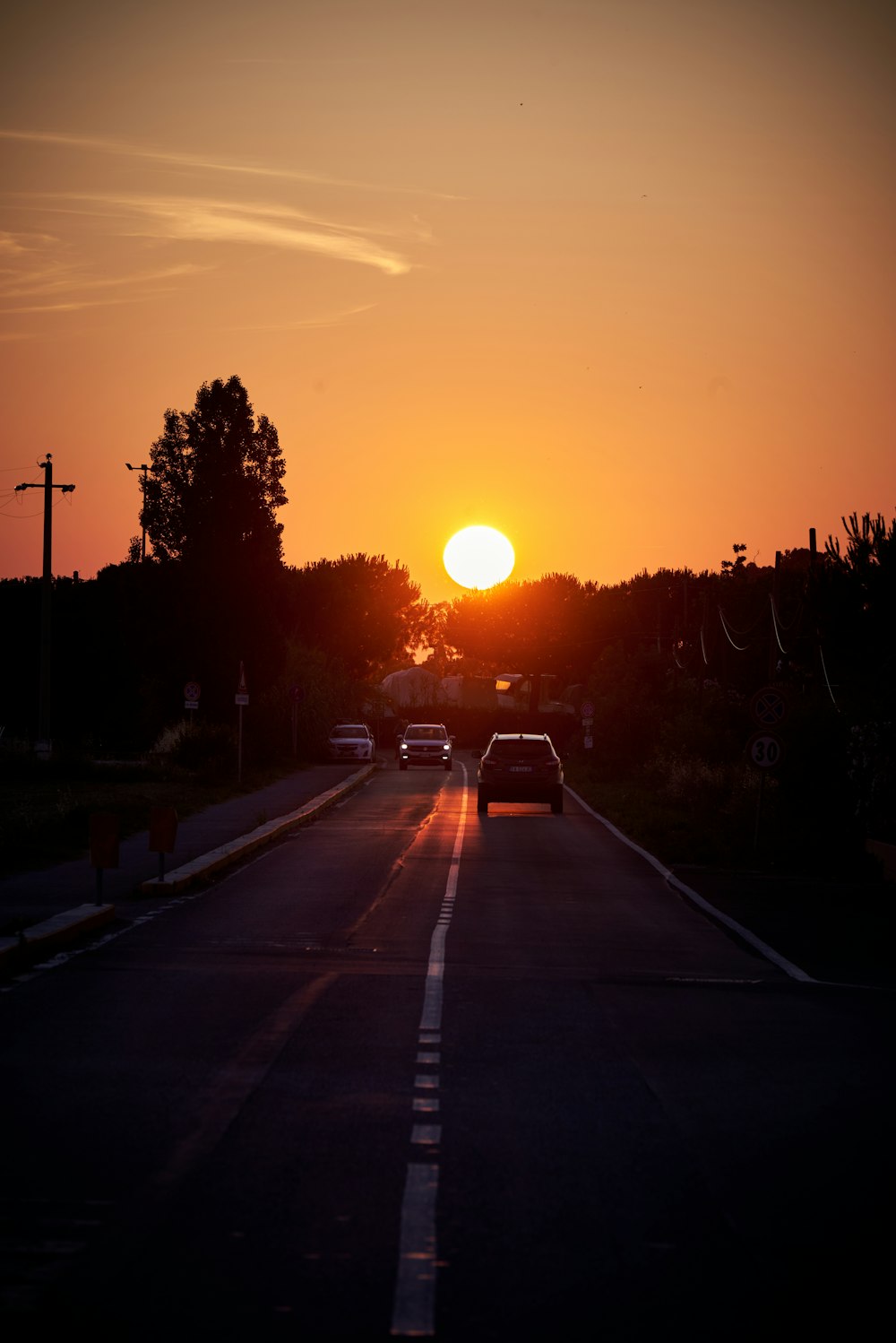 the sun is setting over the horizon of a street