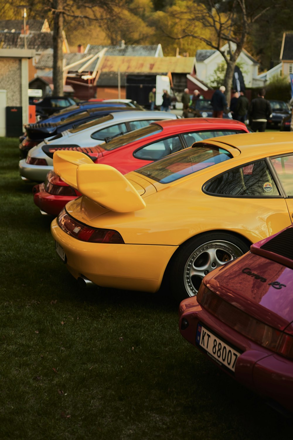 a row of parked cars sitting on top of a lush green field