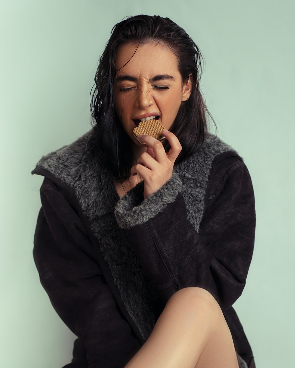 a woman sitting on the floor eating a cookie