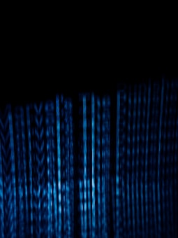 Vertical blue digital lines resembling binary code or data streams on a dark background create a visually striking and abstract pattern.
