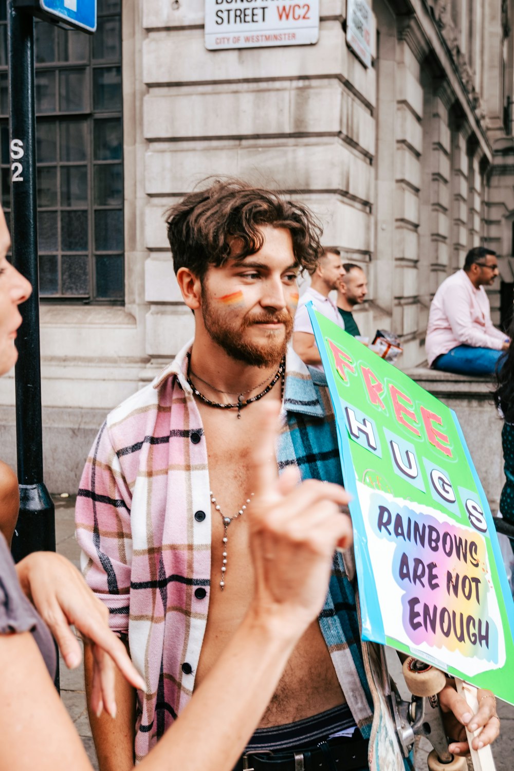 a man holding a sign that says free hugs and rainbows are not enough