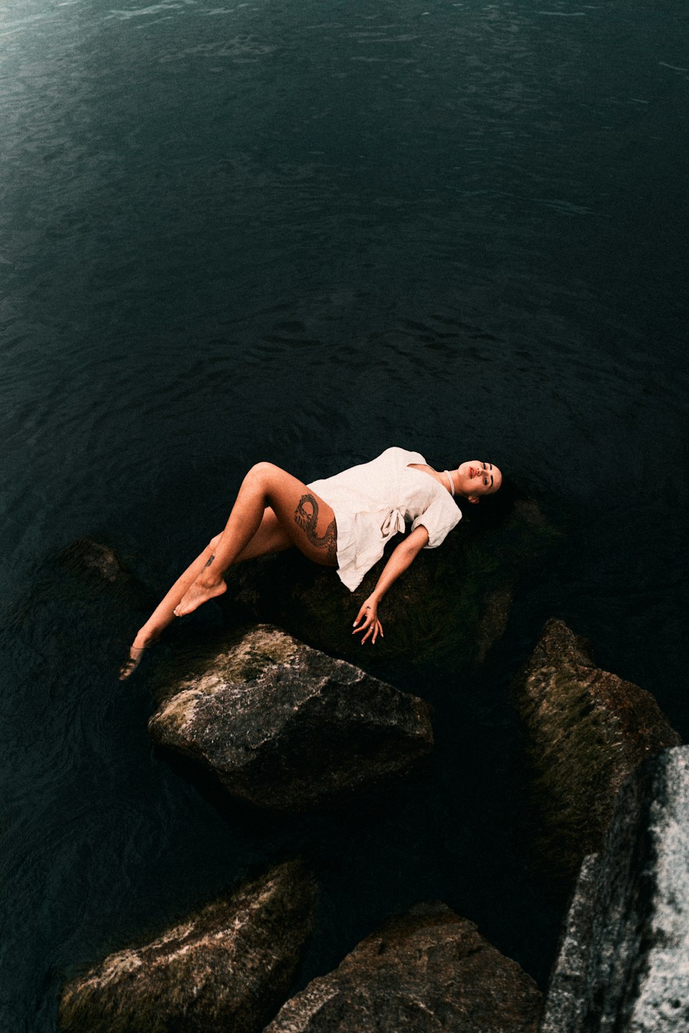 a woman laying on a rock in the water