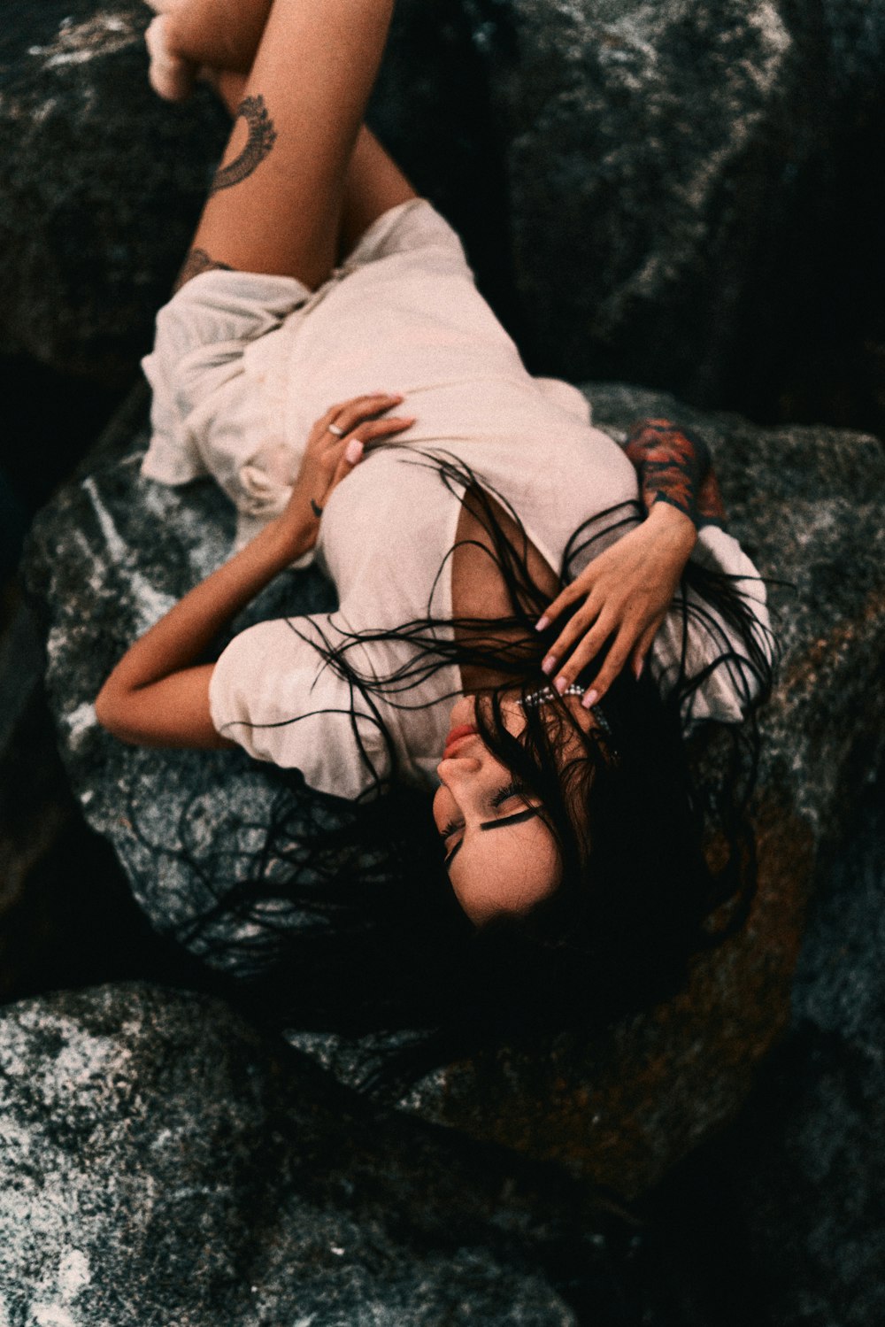a woman laying on top of a large rock
