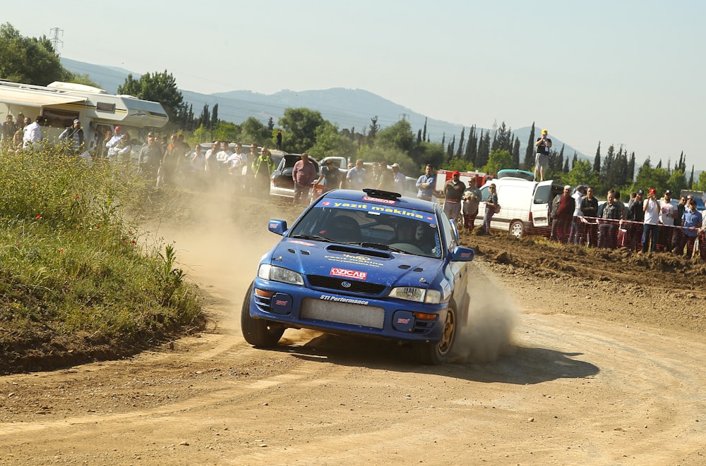 a blue car driving down a dirt road