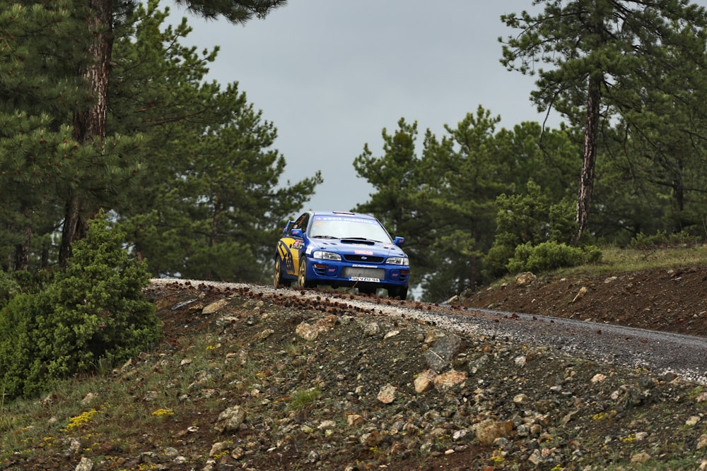 Un'auto da rally che scende da una collina con alberi sullo sfondo