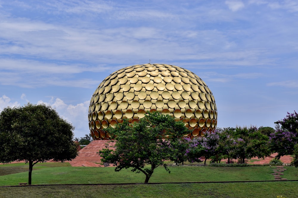 a large golden ball sitting in the middle of a park