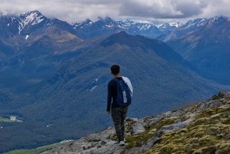 Happy traveler with a suitcase standing in front of a scenic mountain view.