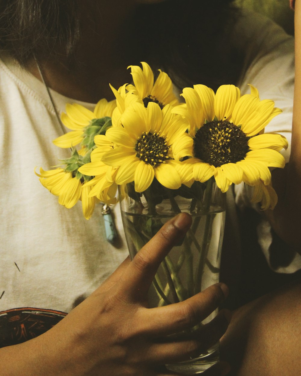 a person holding a vase with yellow flowers in it