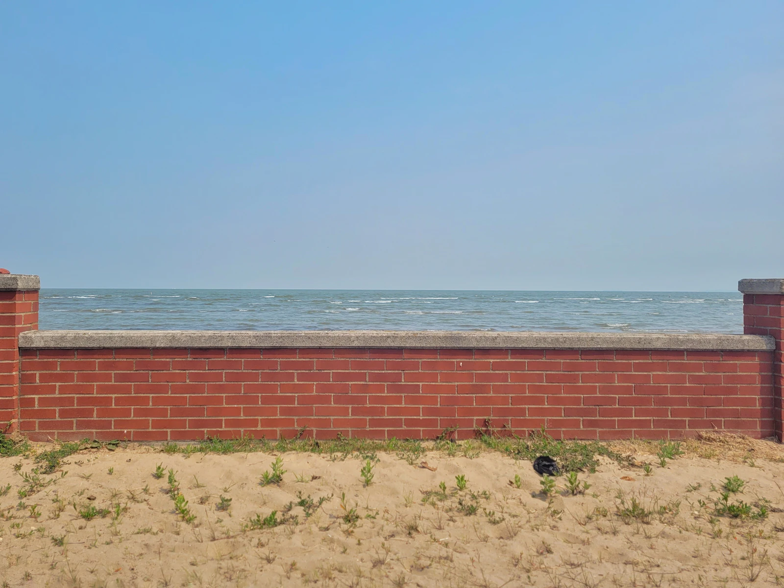 A low brick wall along a Great Lakes shoreline.