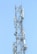 A tall metal communication tower with various antennas and equipment installed on it against a clear blue sky.