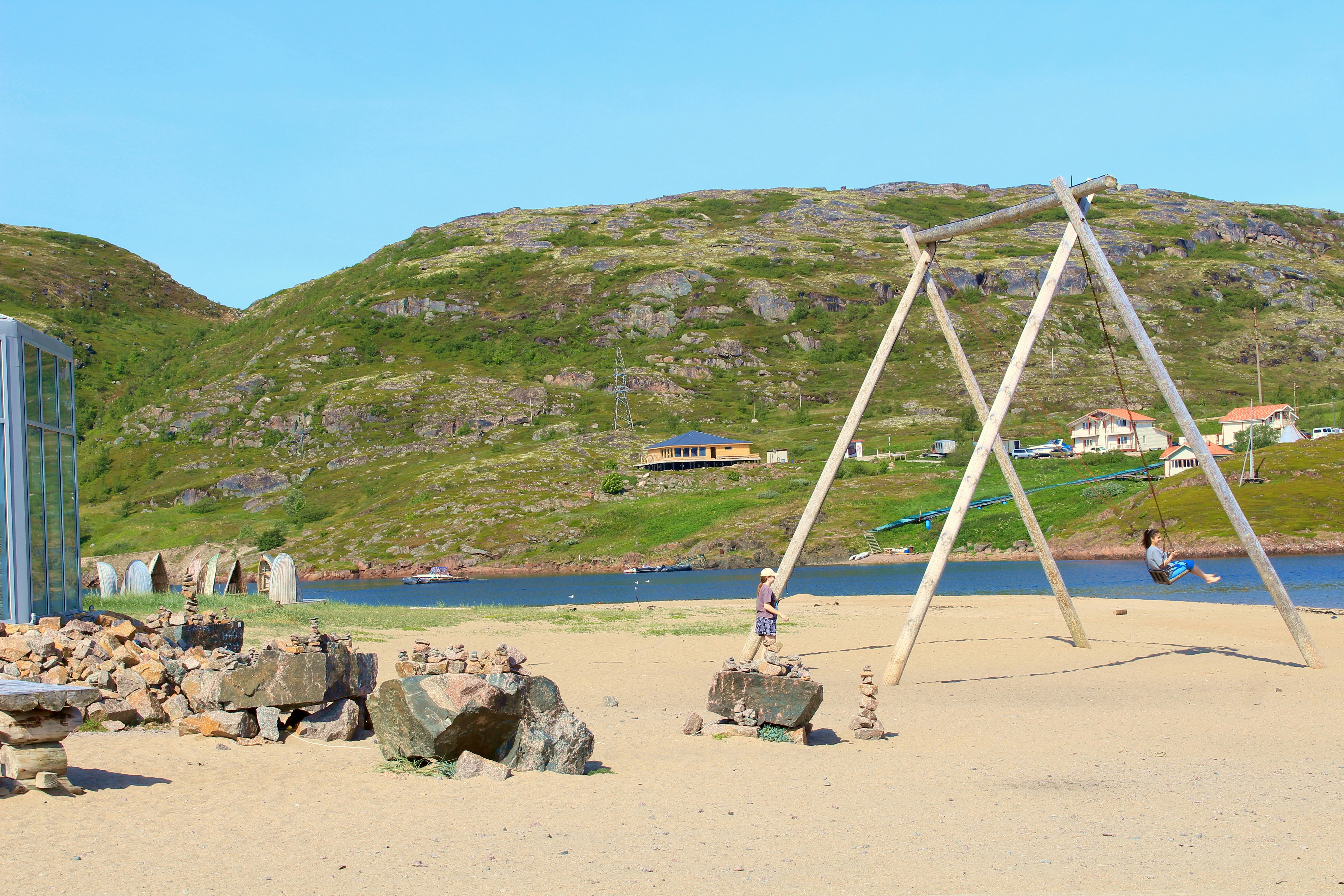 a wooden swing set sitting on top of a sandy beach