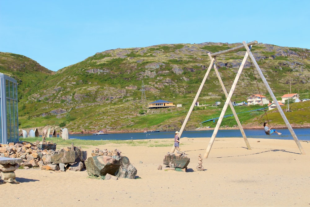 a wooden swing set sitting on top of a sandy beach