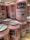 A collection of pink craft beer cans labeled 'Cerdos Voladores' from Barcelona Beer Company. The cans feature cartoon images of a pig wearing sunglasses with angel wings, along with various textual and design elements. The cans are arranged closely together on a wooden surface.