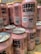 A collection of pink craft beer cans labeled 'Cerdos Voladores' from Barcelona Beer Company. The cans feature cartoon images of a pig wearing sunglasses with angel wings, along with various textual and design elements. The cans are arranged closely together on a wooden surface.