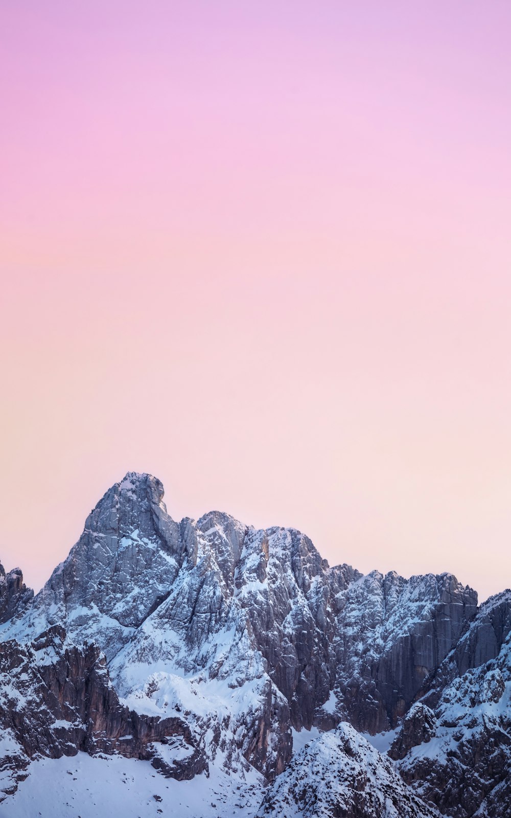 a snowy mountain with a pink sky in the background