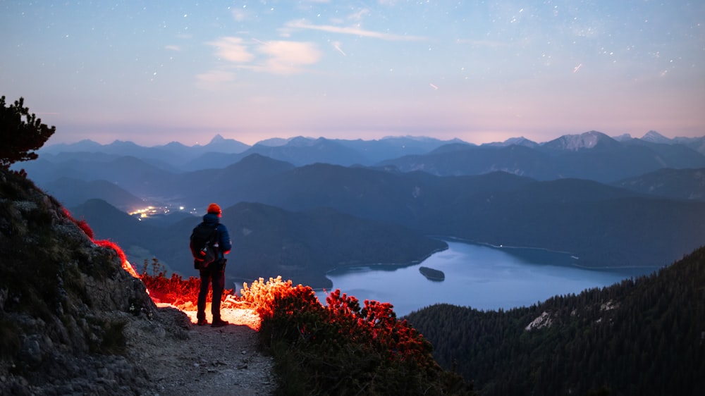 a man standing on top of a mountain next to a fire