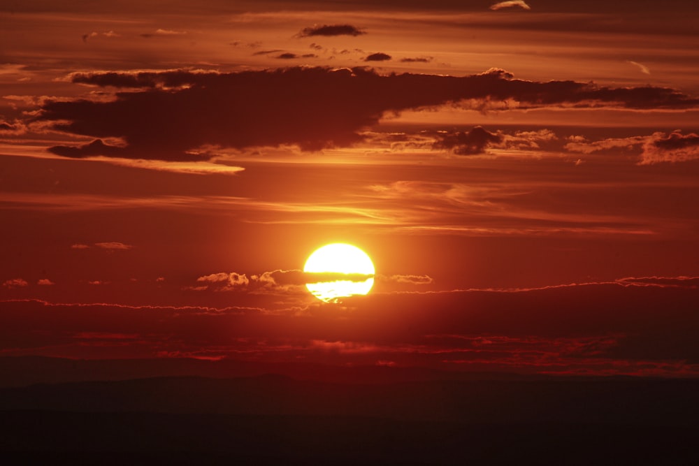 the sun is setting in the sky with clouds