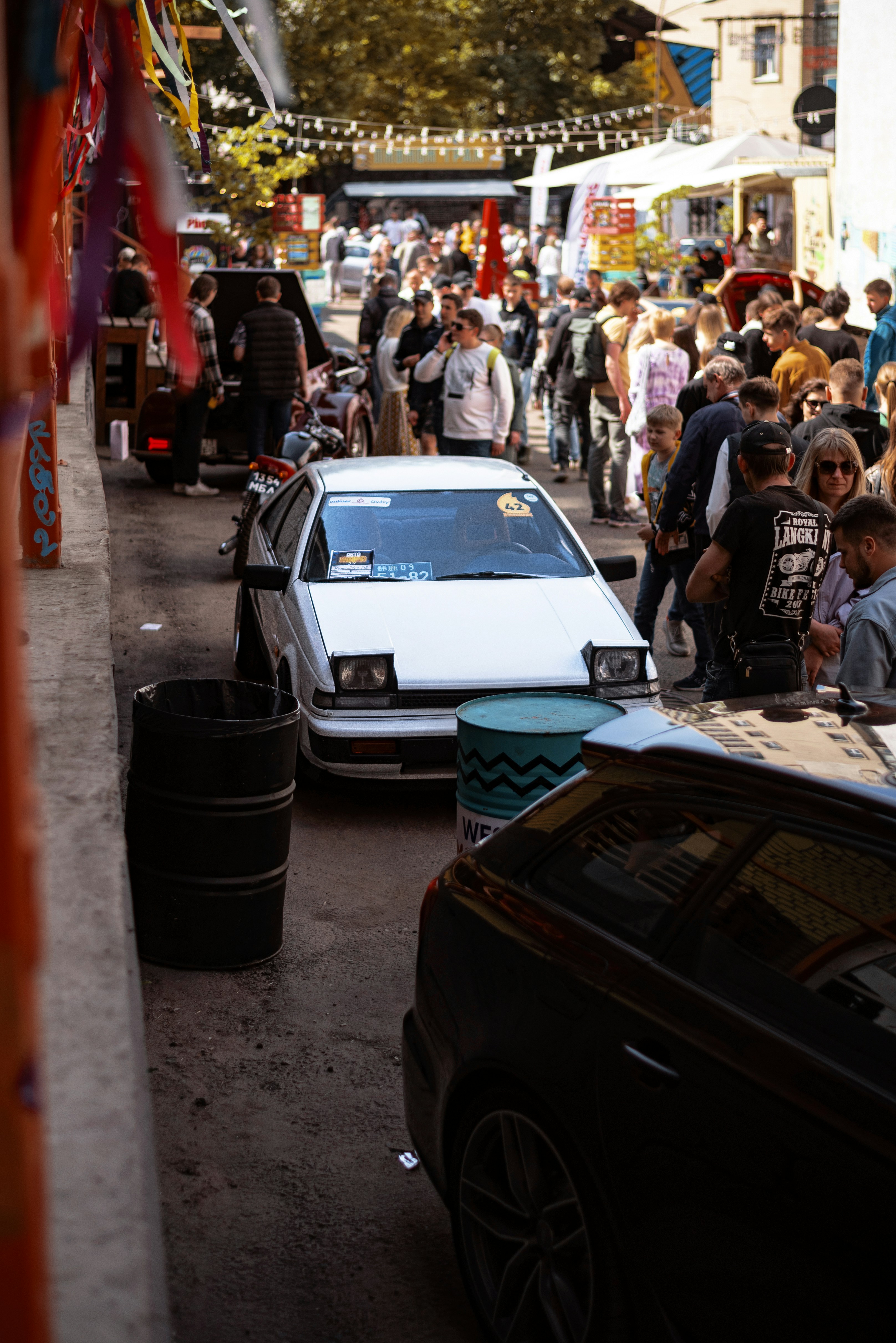 a crowd of people walking down a street next to parked cars