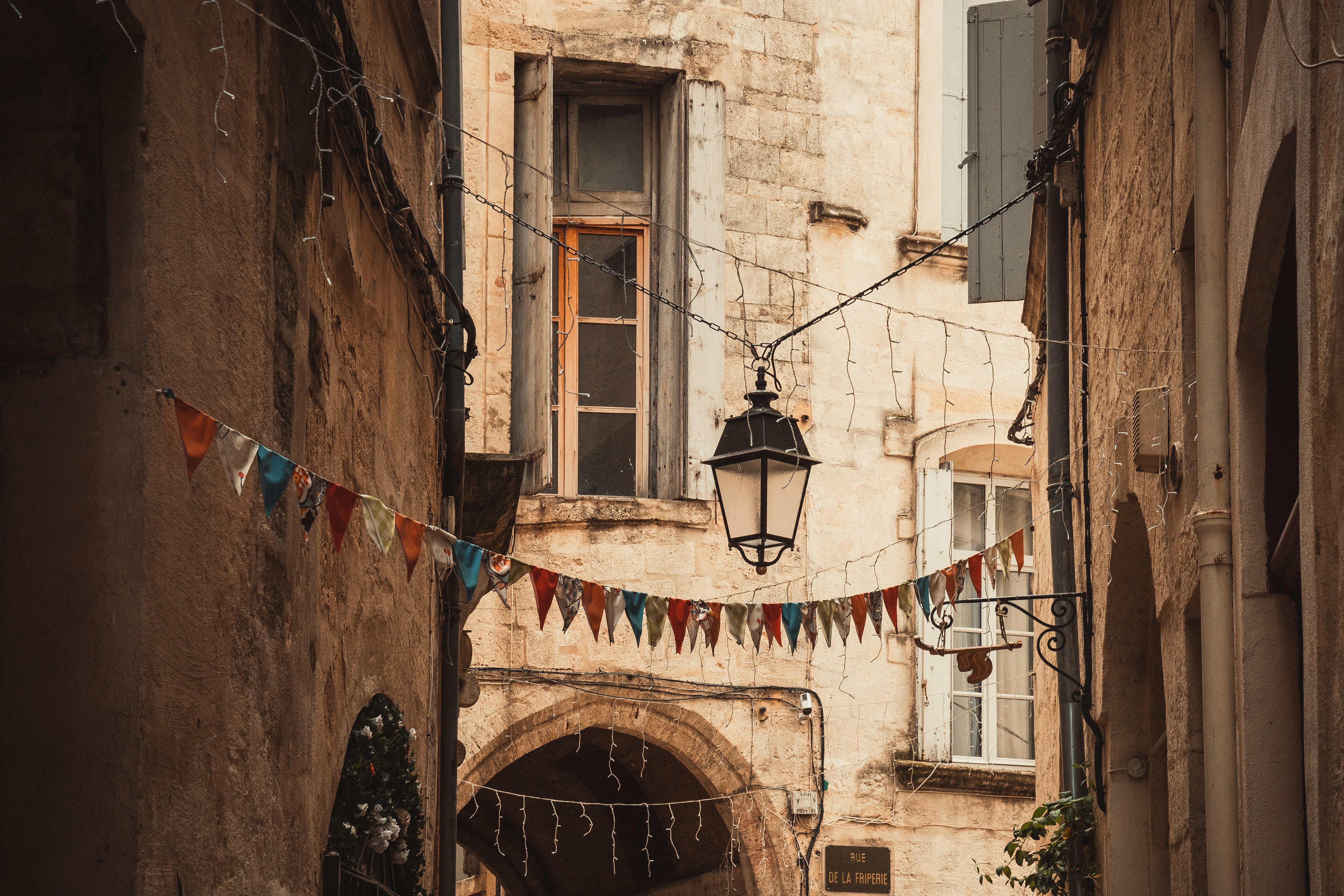 a narrow alleyway with a lamp and flags