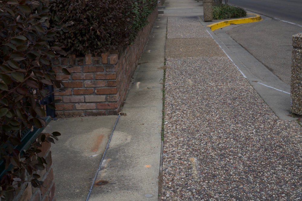 an empty sidewalk next to a brick wall