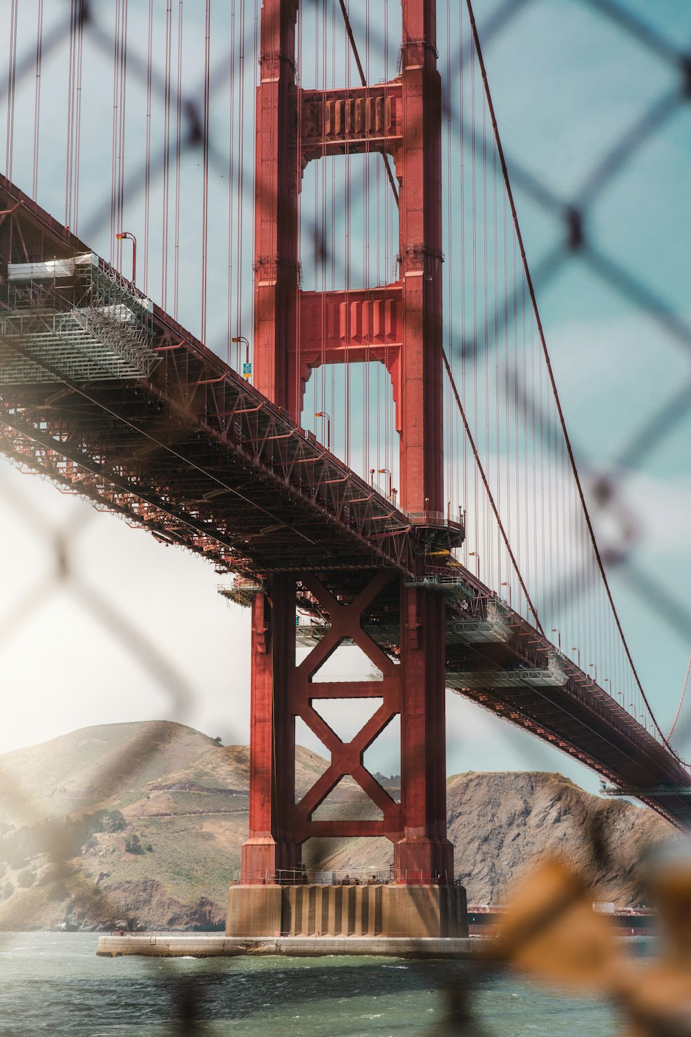 a view of the golden gate bridge through a chain link fence