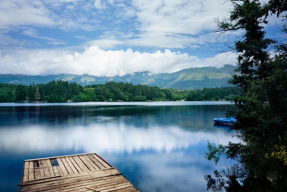 a boat floating on top of a lake next to a wooden dock