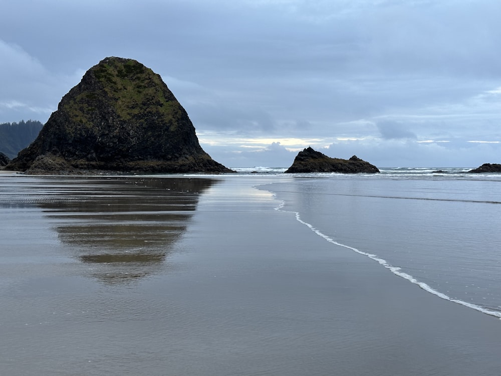 a large rock sitting on top of a beach next to the ocean