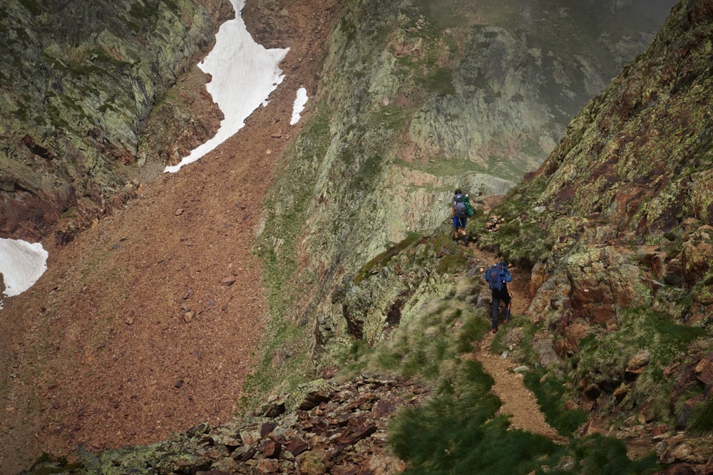 a couple of people hiking up a mountain side